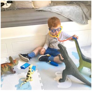 A child is playing doctors with toy dinosaurs at occupational therapy