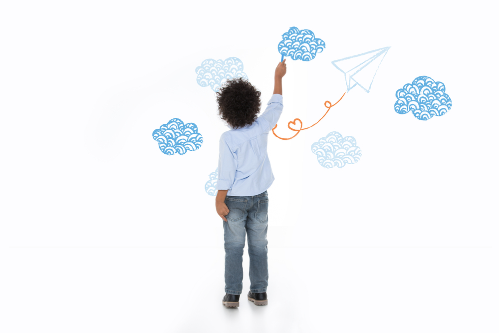 A child is drawing clouds on a wall